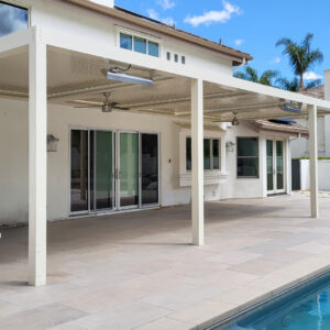 Wide white aluminum louvered roof covering a large poolside patio with dual ceiling fans and infrared heaters attached to a stucco home