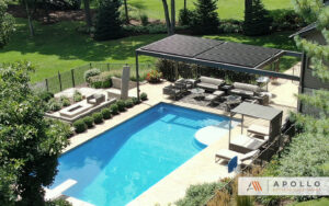 Aerial view of an Apollo aluminum louvered pergola with closed roof shading lounge furniture beside a large backyard pool