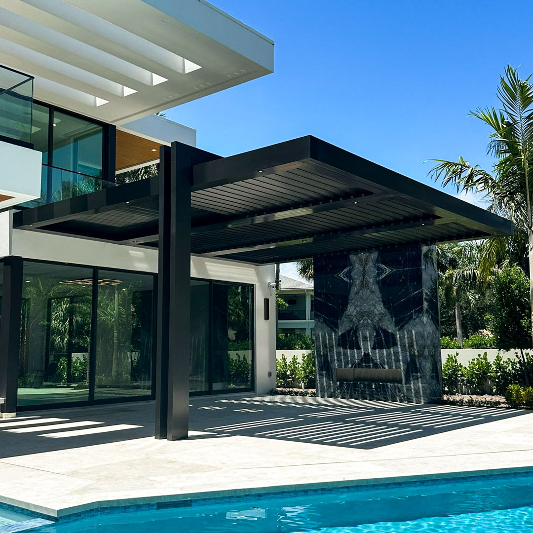 Black aluminum louvered pergola with open slats casting striped shadows across a modern home's patio and pool